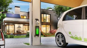 Aufladen eines Elektroautos in der Garage neben dem Haus. Modernes Haus mit Sonnenkollektoren auf dem Dach.